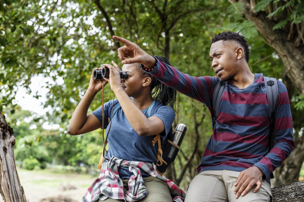 Couple sight seeing with binoculars in the forest